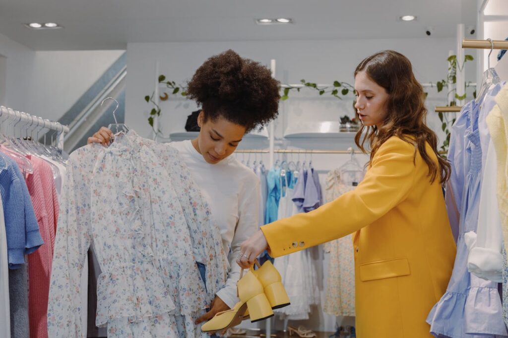 Two women shopping fashionably in a chic boutique with floral and yellow apparel.