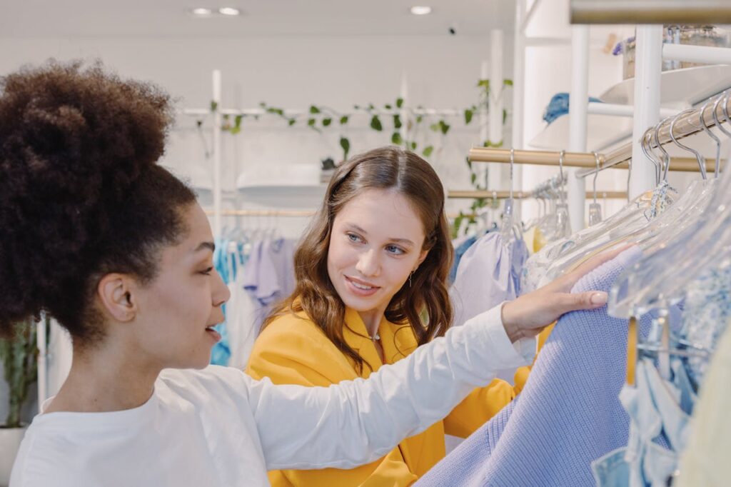 Two women exploring fashion choices at a chic boutique, sharing insights and styles.